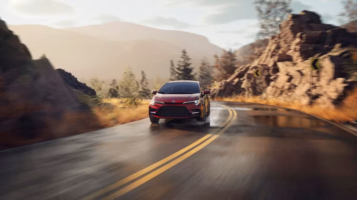 Red Toyota Corolla hybrid accelerating on mountain road